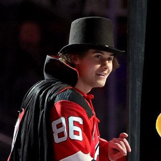 jack hughes in a top hat and cap, smiling towards the camera