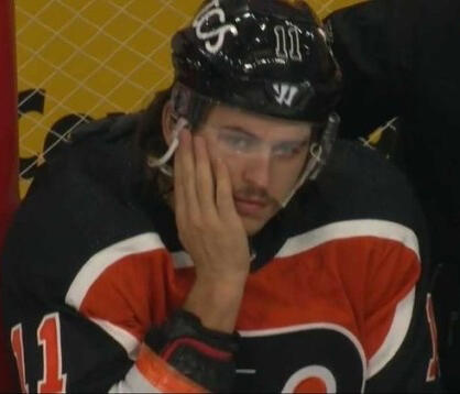 nolan patrick squints against the snowy sky, a green beanie on his head popping out of the photo against his black and grey clothes.